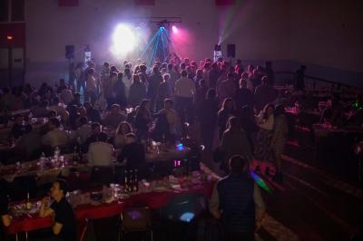 Grande salle en bois avec charpente apparente, éclairages rouges, matériel de sonorisation et espace vide au centre.