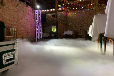 Grande salle en bois avec charpente apparente, éclairages rouges, matériel de sonorisation et espace vide au centre.