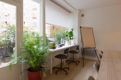 Terrasse en pierre avec mobilier de jardin, entourée de plantes en pots, donnant sur des immeubles en briques.