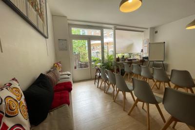 Terrasse en pierre avec mobilier de jardin, entourée de plantes en pots, donnant sur des immeubles en briques.