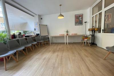 Terrasse en pierre avec mobilier de jardin, entourée de plantes en pots, donnant sur des immeubles en briques.