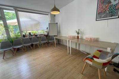 Terrasse en pierre avec mobilier de jardin, entourée de plantes en pots, donnant sur des immeubles en briques.