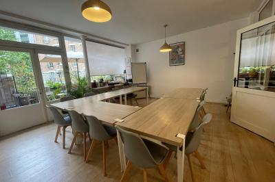 Terrasse en pierre avec mobilier de jardin, entourée de plantes en pots, donnant sur des immeubles en briques.