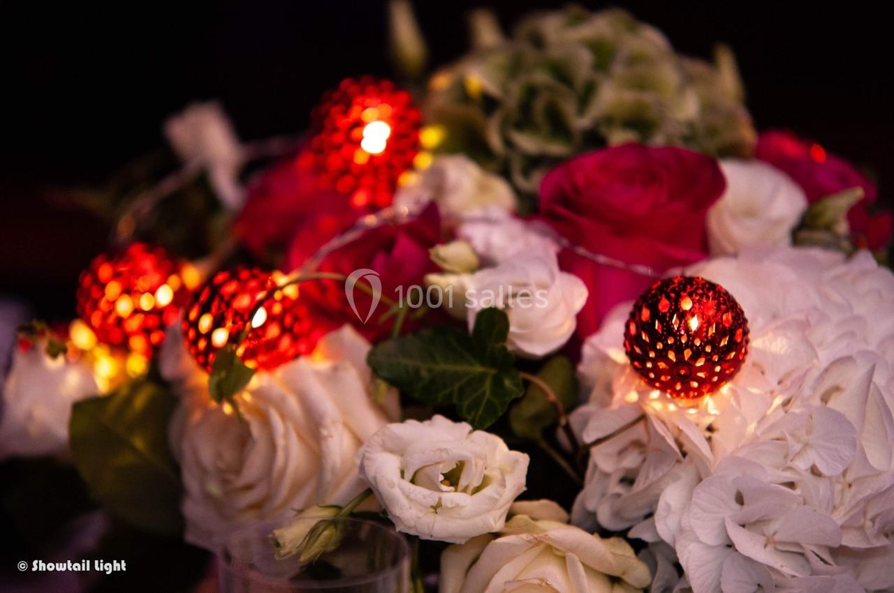 Bouquet de roses rouges et blanches décoré de petites lumières rouges scintillantes.