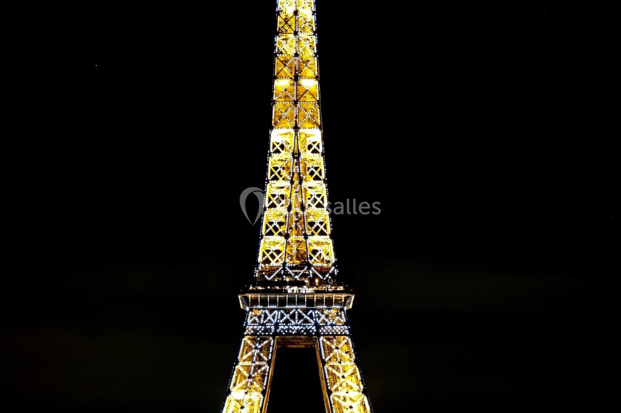 Tour Eiffel illuminée de nuit avec le mot ’MERCI’ affiché, sur fond de ciel sombre.