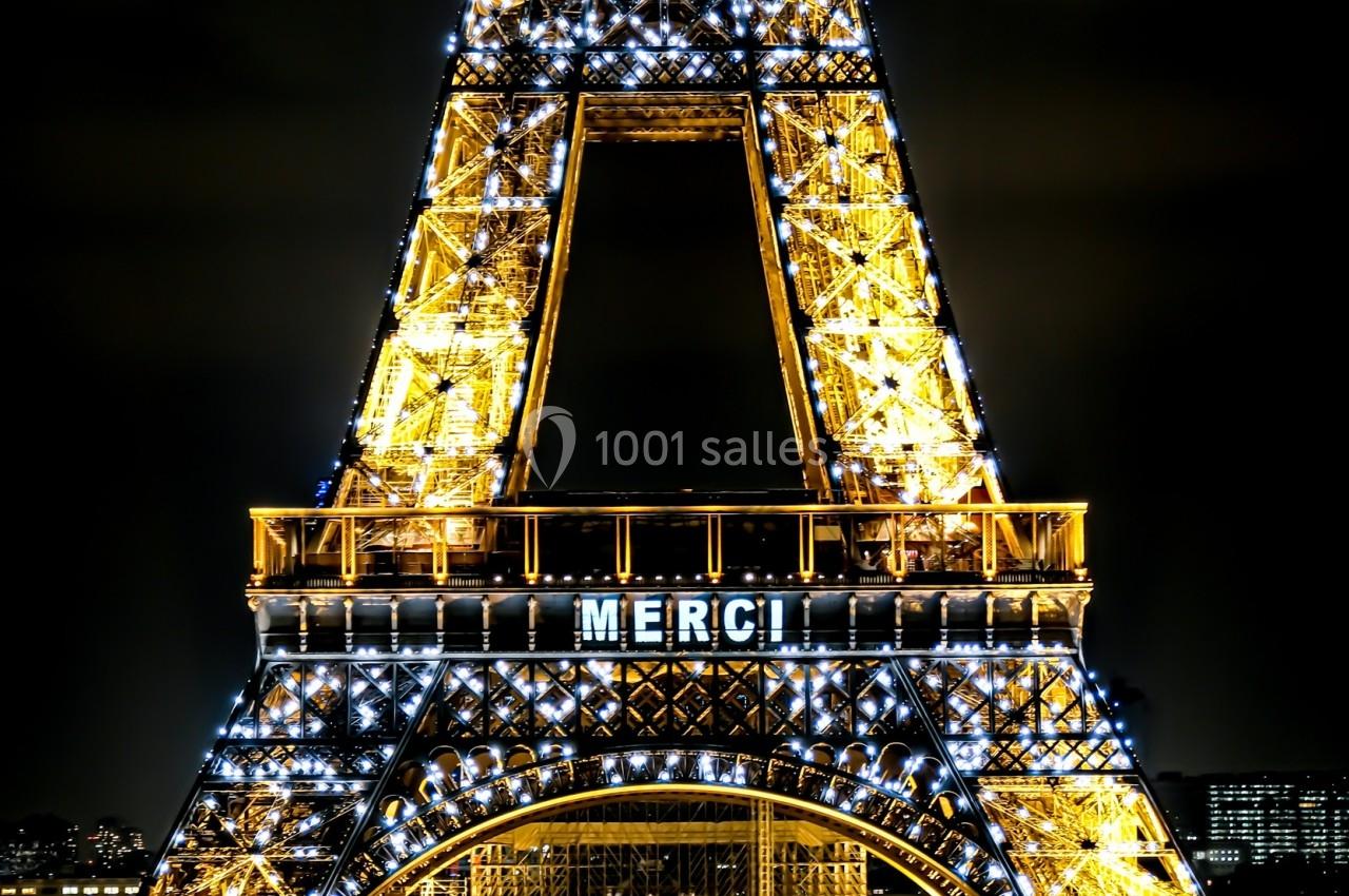 Tour Eiffel illuminée de nuit avec le mot ’MERCI’ affiché, et le Trocadéro visible en arrière-plan.