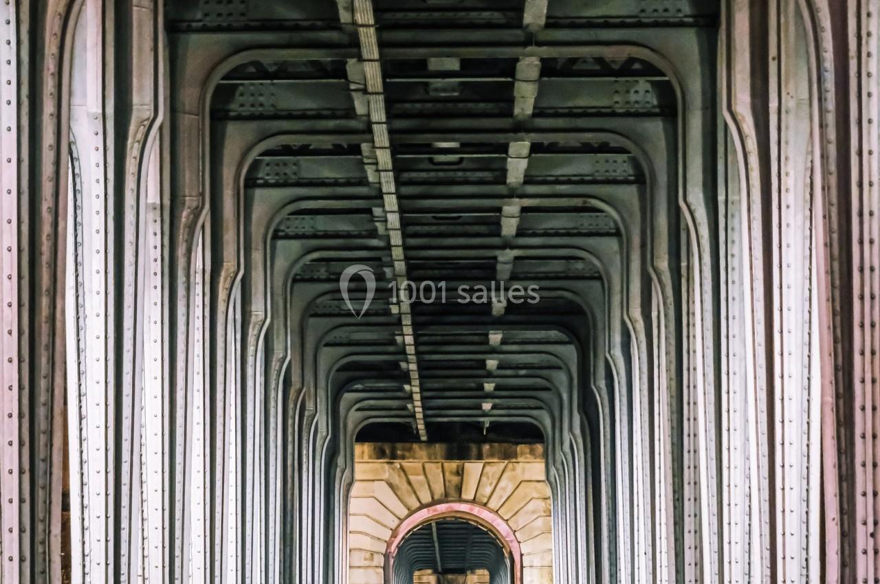 Vue symétrique d'un pont métallique avec une route centrale et des arches alignées en perspective.