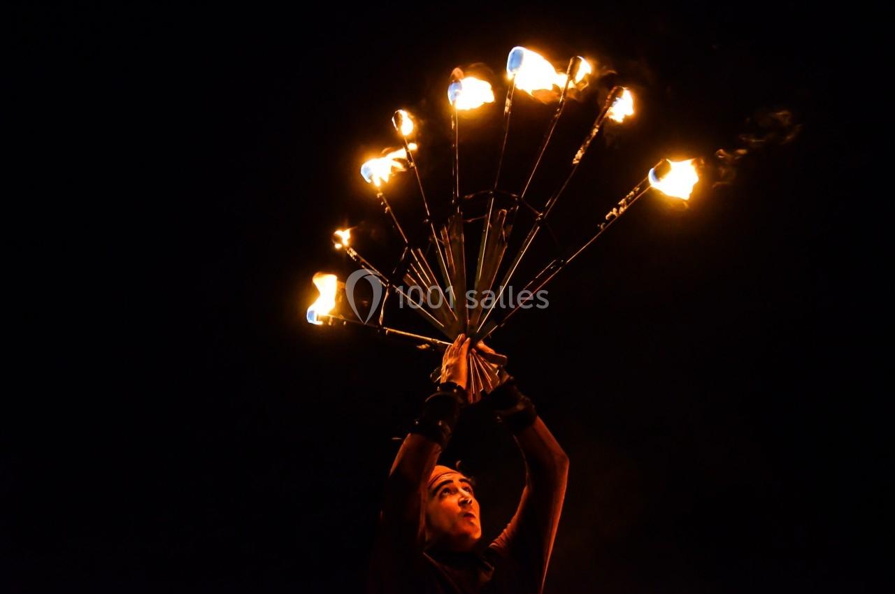 Personne jonglant avec des torches enflammées dans l'obscurité, créant un effet lumineux spectaculaire.
