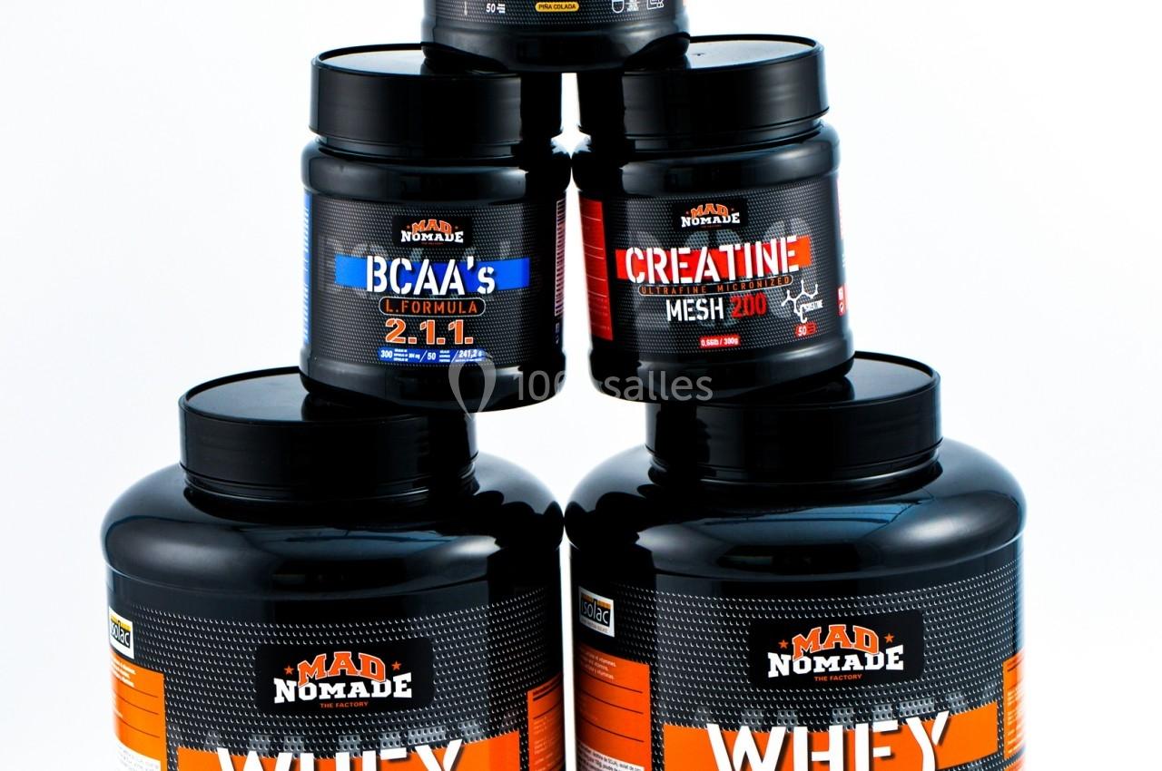 Pots de compléments alimentaires comprenant whey, créatine, BCAA et acides aminés, empilés sur fond blanc.