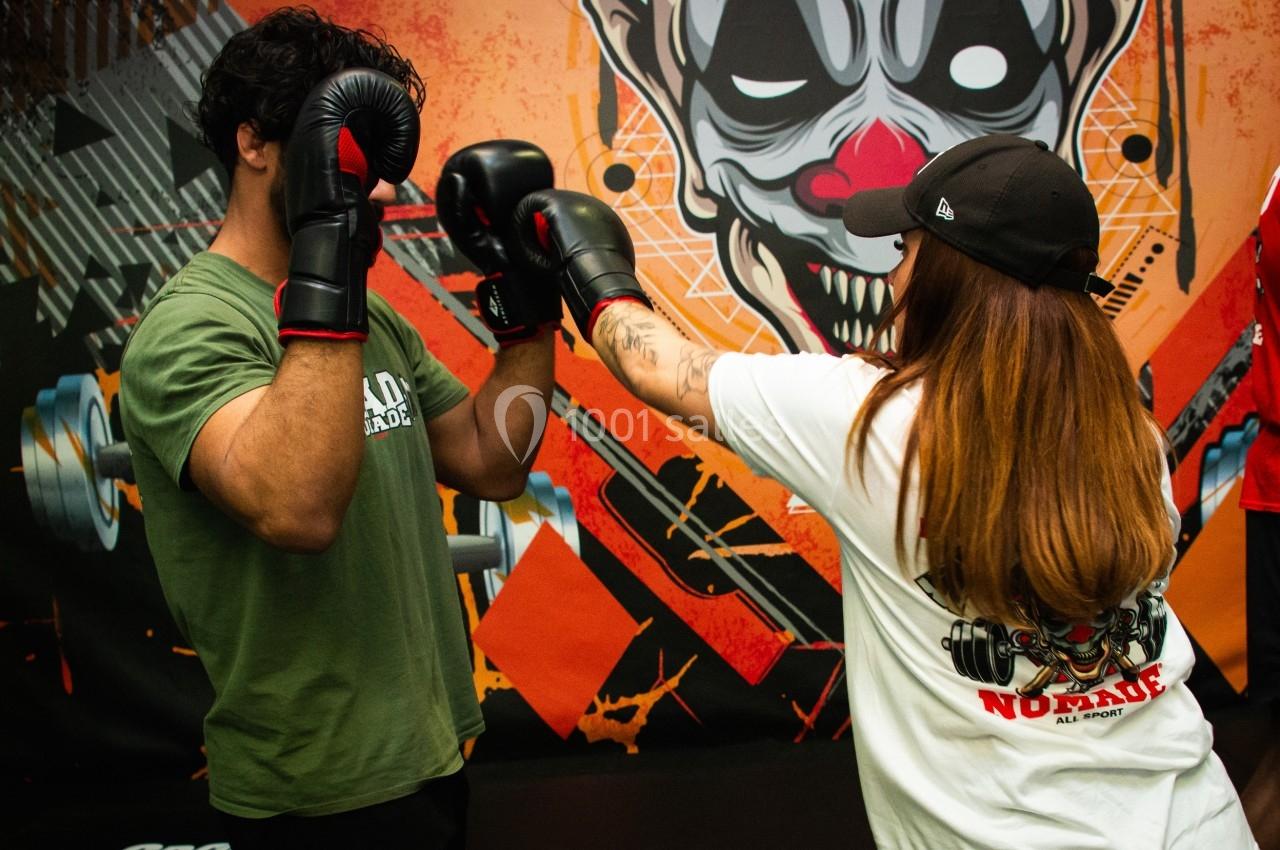 Un homme et une femme s'entraînent à la boxe dans une salle décorée avec un motif de clown coloré.