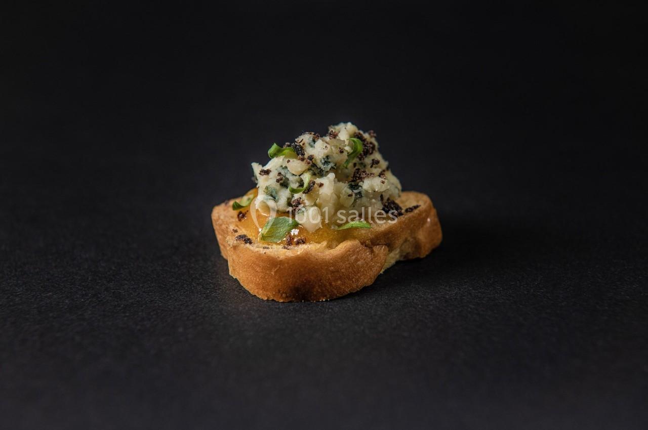 Toast garni d'une préparation crémeuse aux herbes et graines, posé sur une surface sombre.