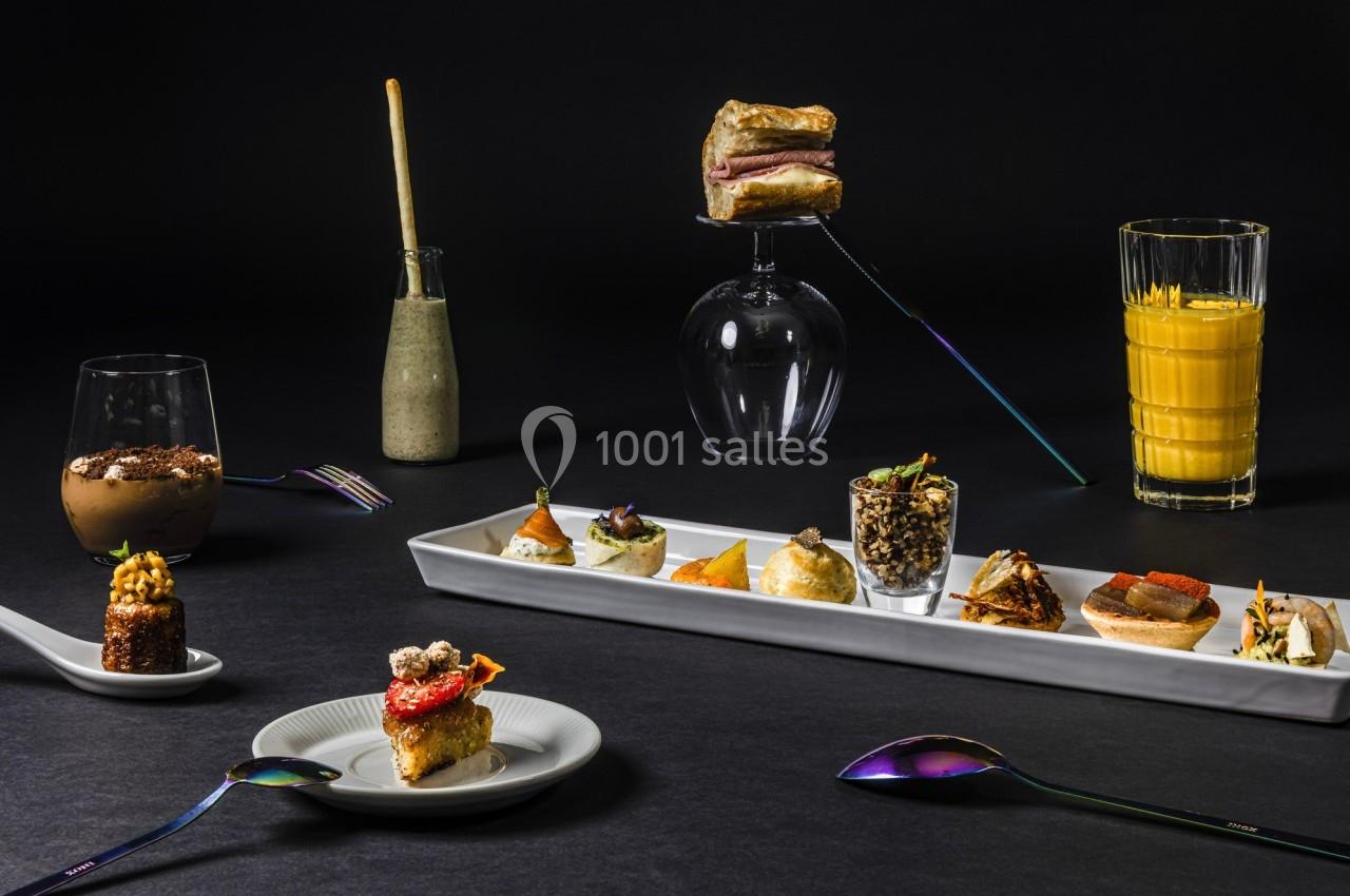 Assortiment de plats gastronomiques et boissons présentés sur une table sombre avec des couverts colorés.