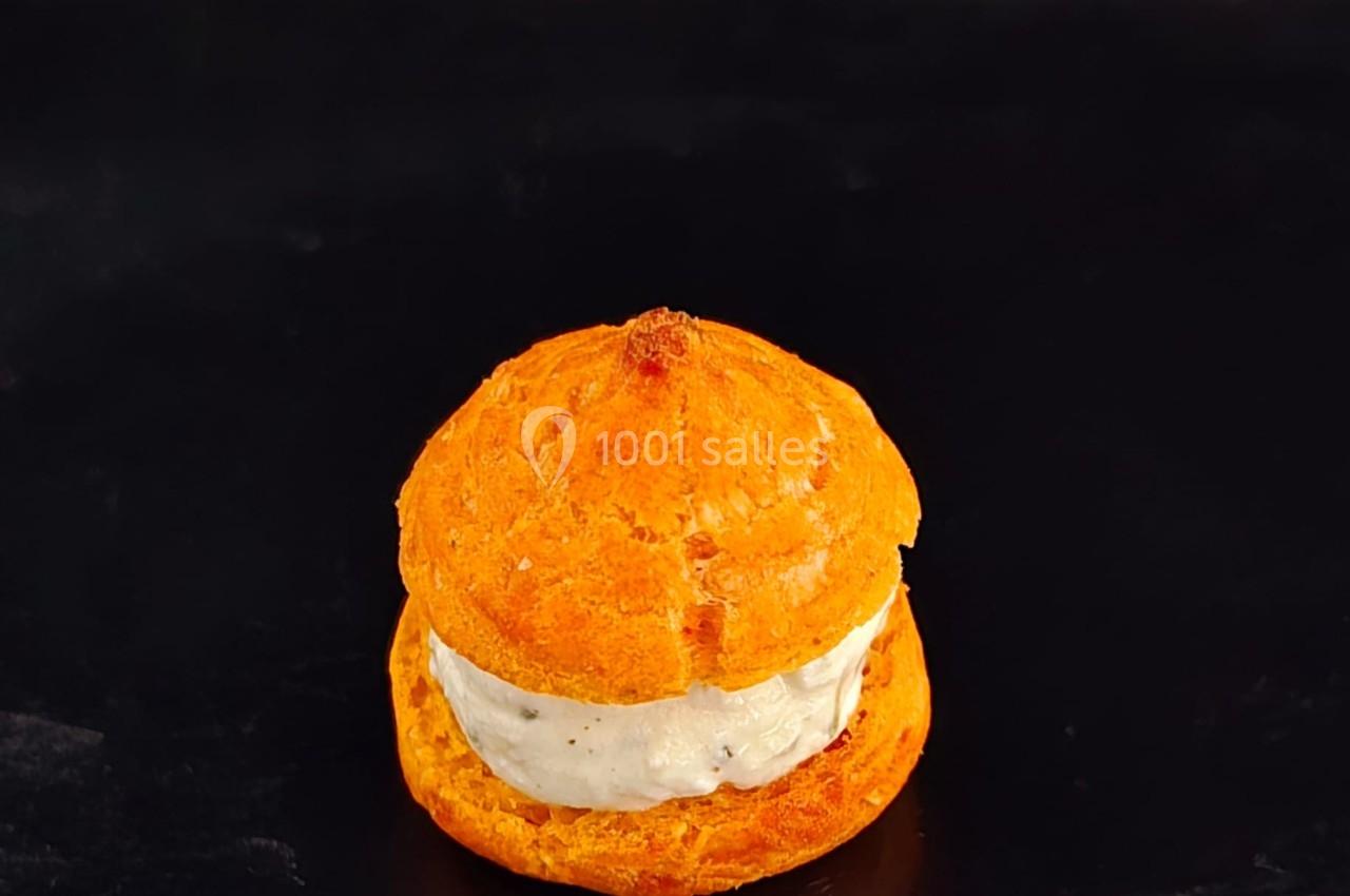 Chou garni de crème salée, posé sur une surface noire avec un fond sombre.
