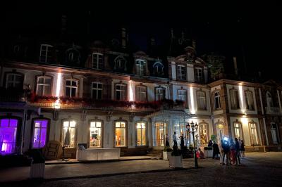Salle de réception lumineuse avec tables rondes dressées, grandes baies vitrées et structure métallique apparente.