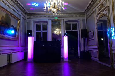 Salle de réception lumineuse avec tables rondes dressées, grandes baies vitrées et structure métallique apparente.