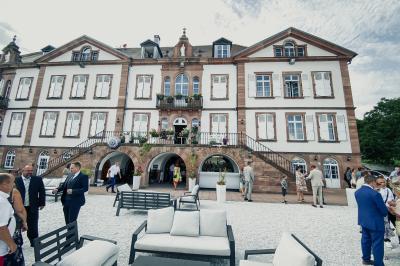 Salle de réception lumineuse avec tables rondes dressées, grandes baies vitrées et structure métallique apparente.