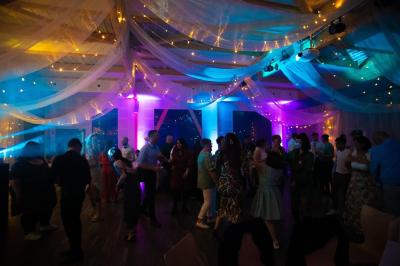 Salle de réception lumineuse avec tables rondes dressées, grandes baies vitrées et structure métallique apparente.