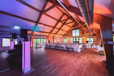 Salle de réception lumineuse avec tables rondes dressées, grandes baies vitrées et structure métallique apparente.