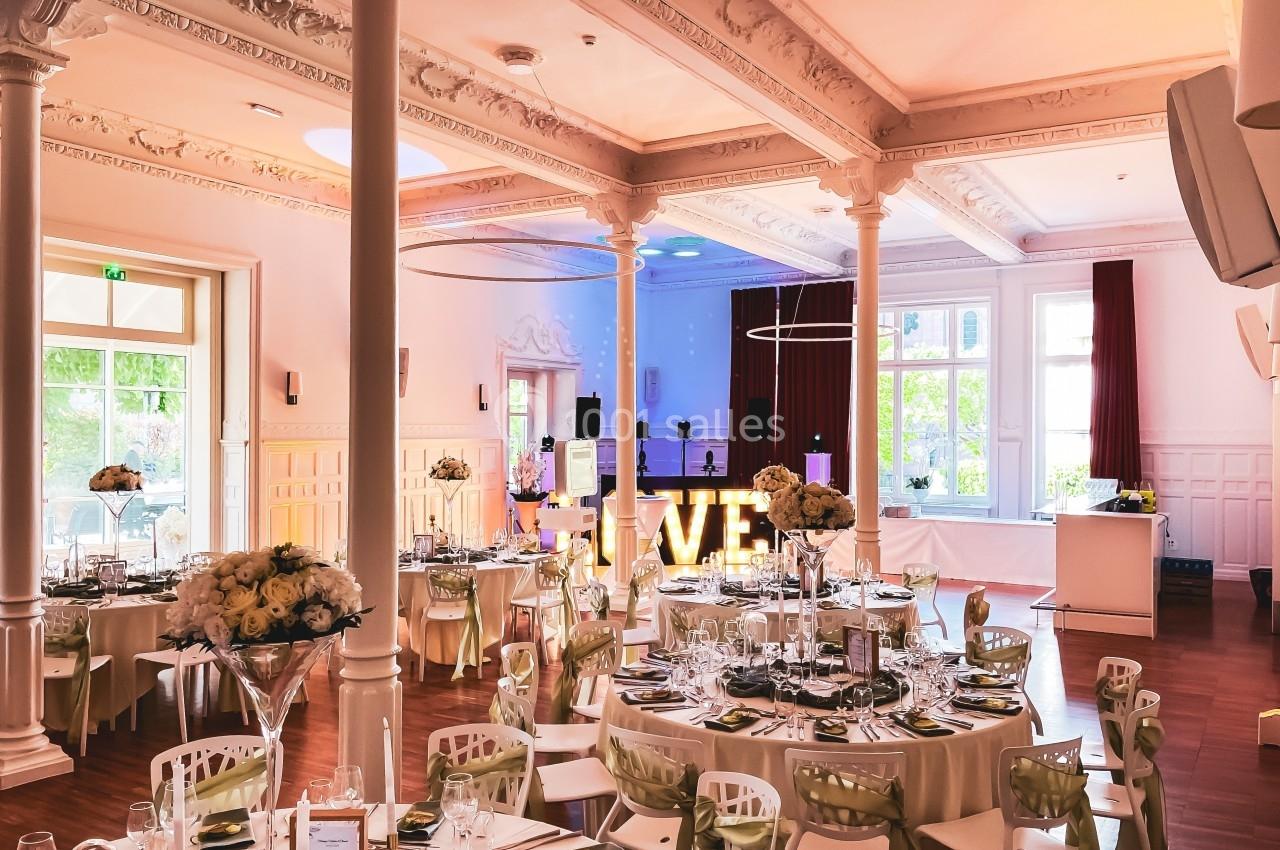 Salle de réception élégante avec tables dressées, décorations florales et enseigne lumineuse ’LOVE’.