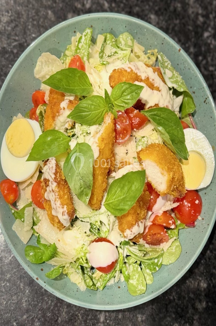 Salade composée avec poulet pané, tomates cerises, œufs durs, feuilles de basilic et copeaux de fromage.