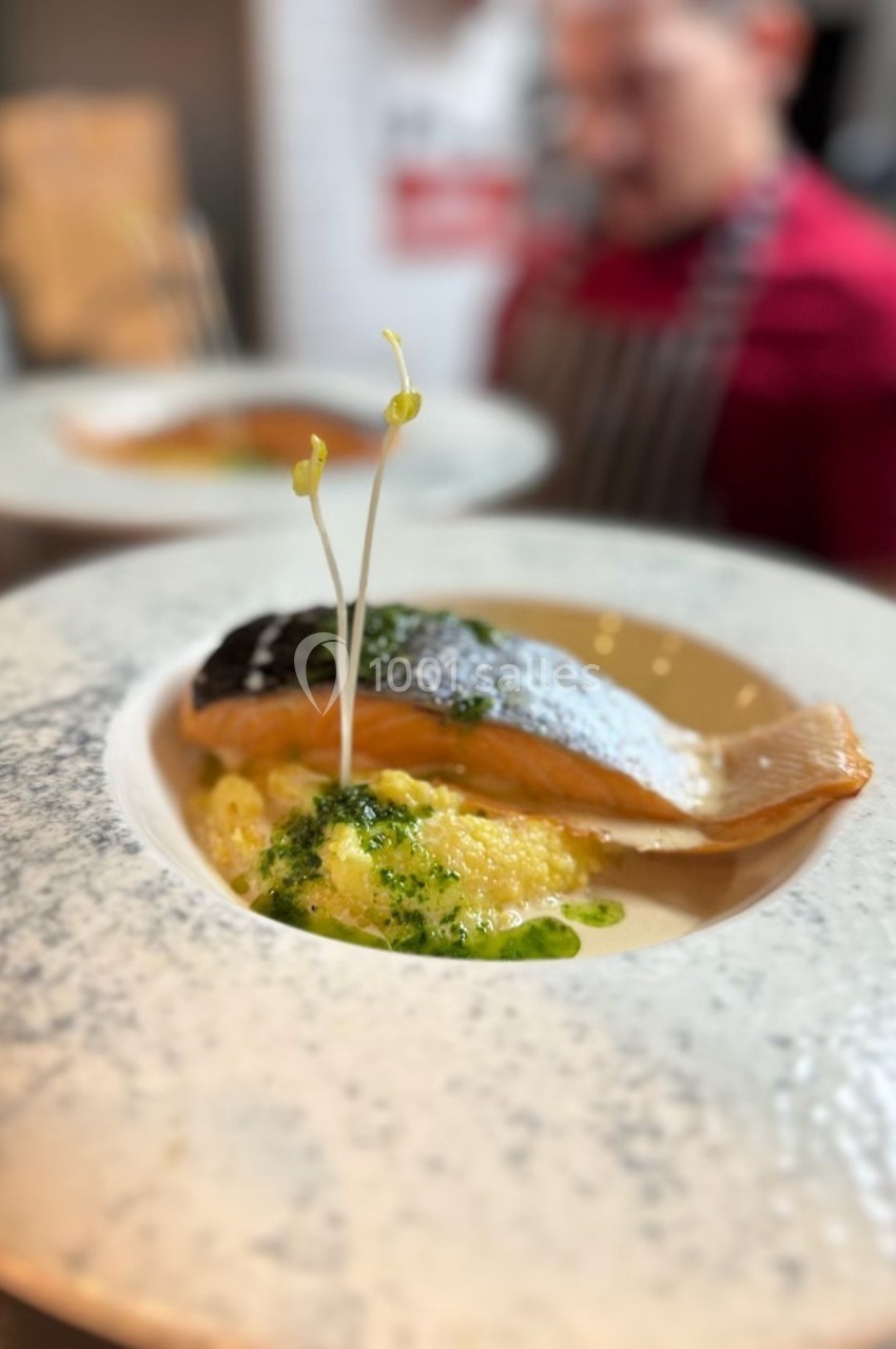 Filet de saumon grillé servi sur un lit de purée, garni de sauce verte et de jeunes pousses.