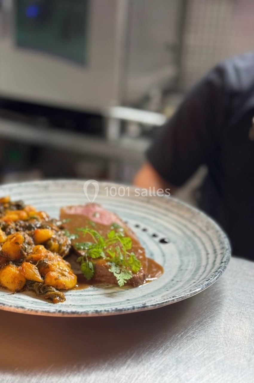 Assiette de gnocchis aux légumes et viande nappée de sauce, servie sur une table en cuisine.