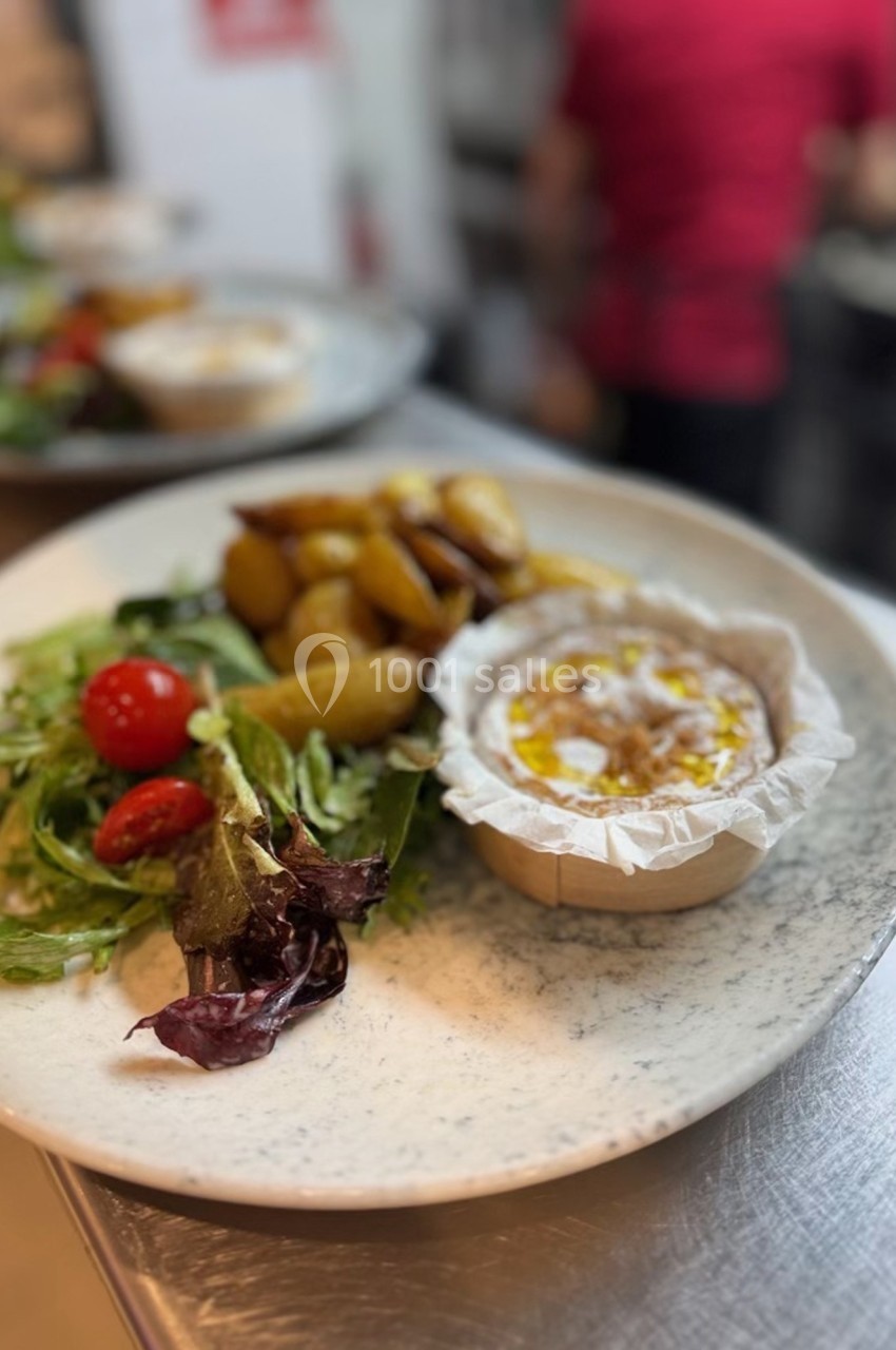 Assiette composée d'un camembert chaud, de pommes de terre rôties et d'une salade verte avec tomates cerises.
