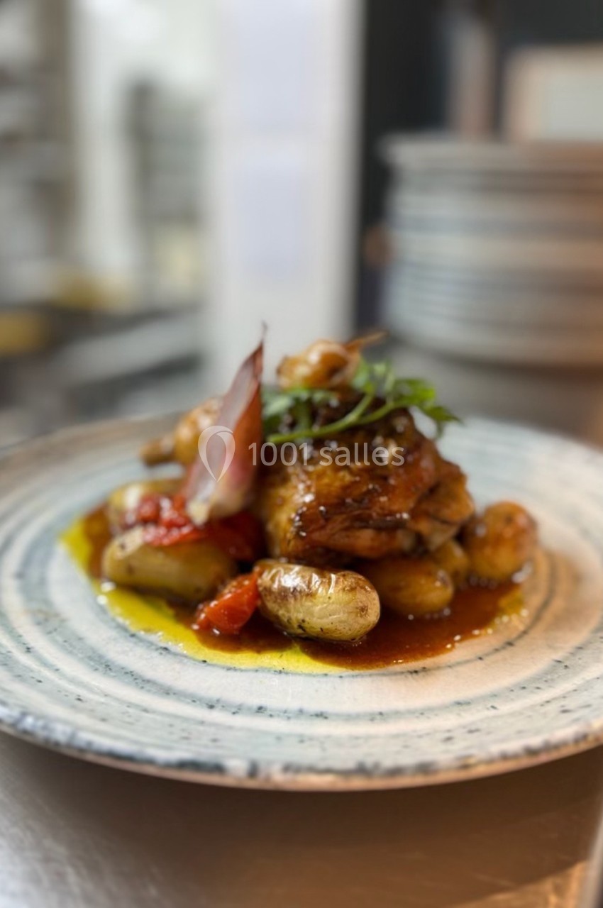 Assiette de poulet rôti accompagné de pommes de terre, tomates confites et herbes fraîches, dressée sur une table.