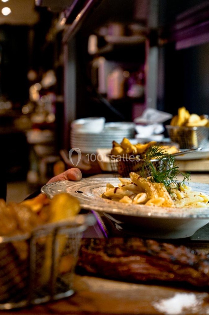 Assiette de pâtes garnie d'herbes fraîches servie avec des frites dans un restaurant à l'ambiance tamisée.