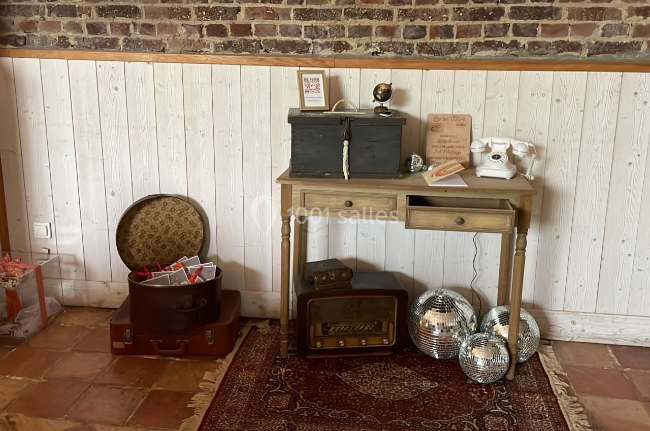Un bureau en bois avec des objets vintage, entouré de valises, de boules à facettes et d'un mur en briques et lambris.