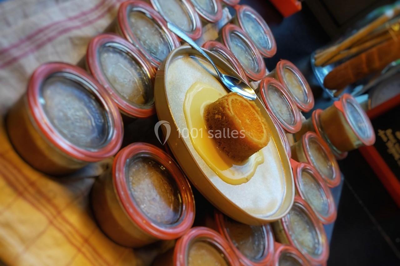 Dessert individuel au sirop sur une assiette, entouré de pots en verre fermés contenant une préparation.