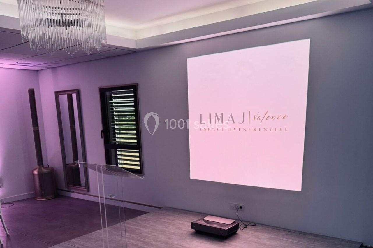 Salle moderne avec écran de projection affichant ’Limaj Valence’, éclairage tamisé et mobilier minimaliste.