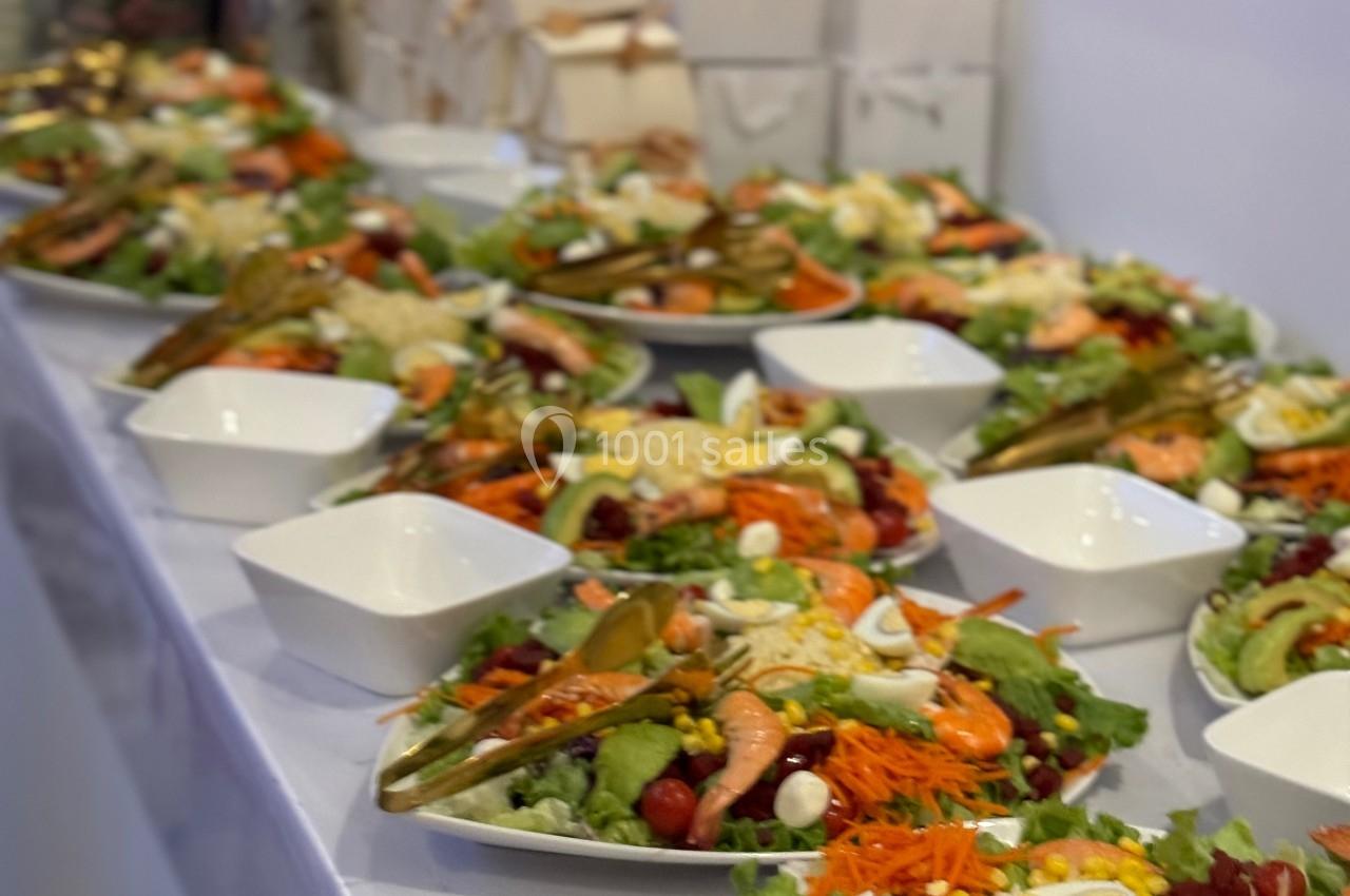 Assiettes de salades composées avec légumes, crevettes et œufs, alignées sur une table dans un cadre de réception.