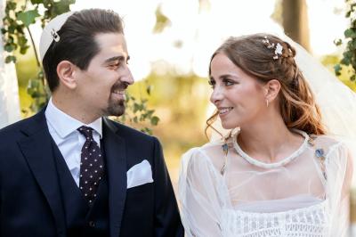 Un couple en tenue de mariage pose dans une forêt verdoyante, éclairée par une lumière douce.