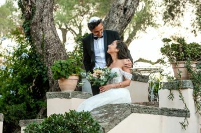 Un couple en tenue de mariage pose dans une forêt verdoyante, éclairée par une lumière douce.