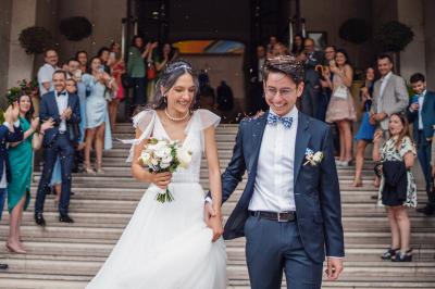 Un couple en tenue de mariage pose dans une forêt verdoyante, éclairée par une lumière douce.