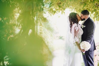 Un couple en tenue de mariage pose dans une forêt verdoyante, éclairée par une lumière douce.