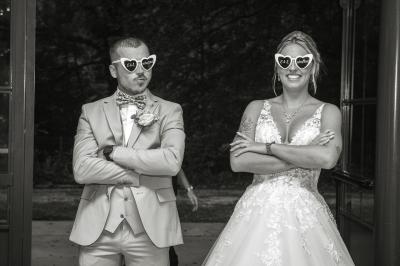 Un couple en tenue de mariage pose dans une forêt verdoyante, éclairée par une lumière douce.