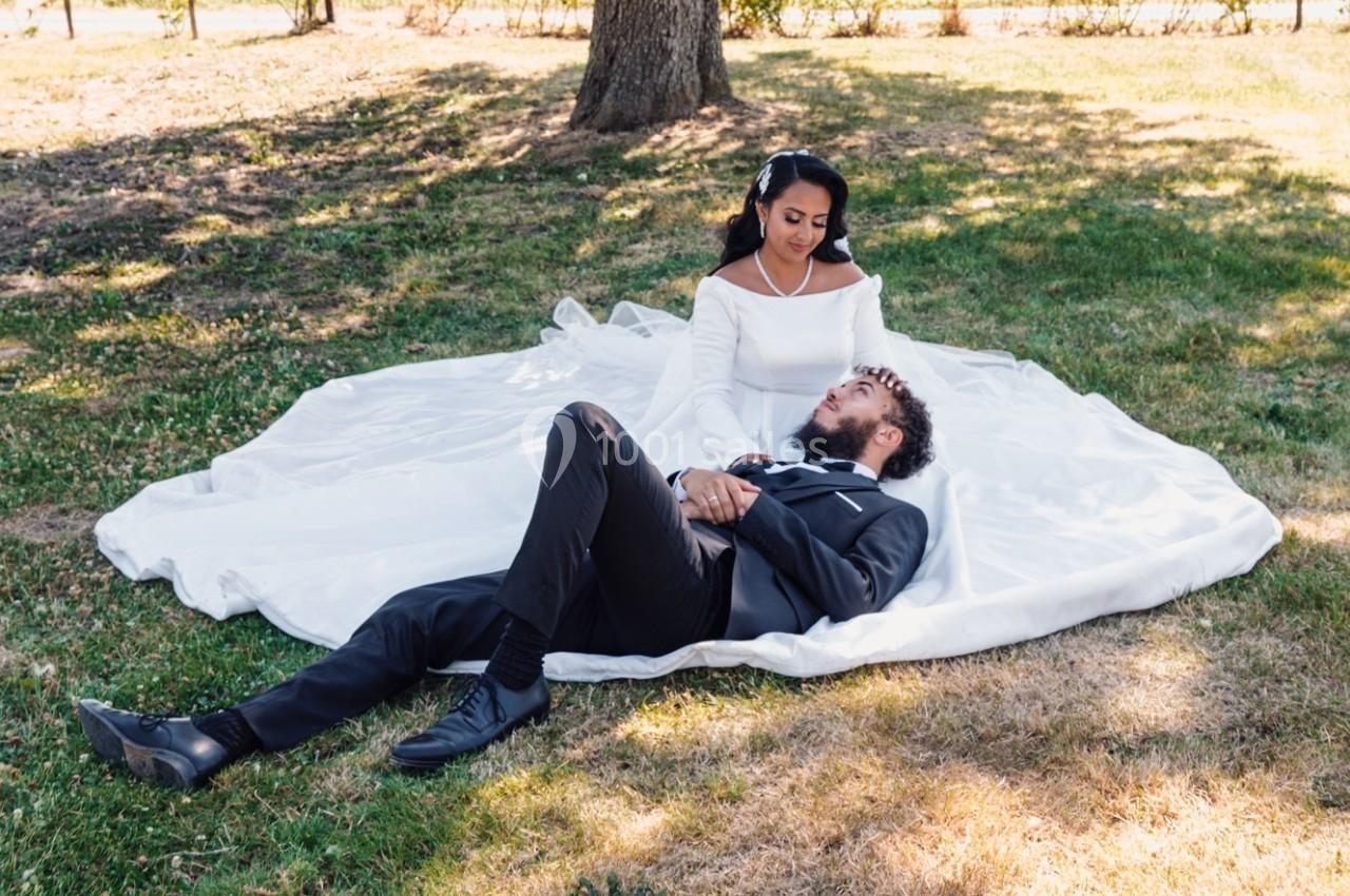 Une femme en robe blanche est assise sur l'herbe, un homme en costume allongé près d'elle.
