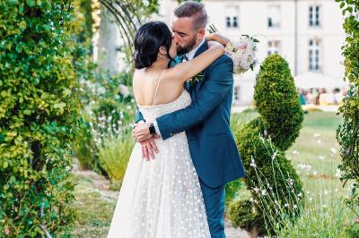 Un couple en tenue de mariage pose dans une forêt verdoyante, éclairée par une lumière douce.