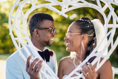 Un couple en tenue de mariage pose dans une forêt verdoyante, éclairée par une lumière douce.