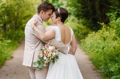 Un couple en tenue de mariage pose dans une forêt verdoyante, éclairée par une lumière douce.