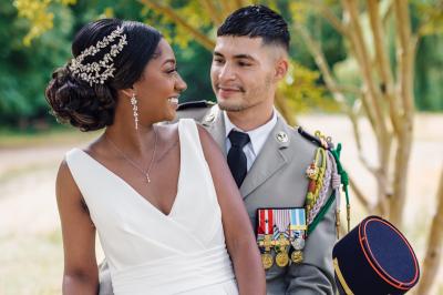 Un couple en tenue de mariage pose dans une forêt verdoyante, éclairée par une lumière douce.