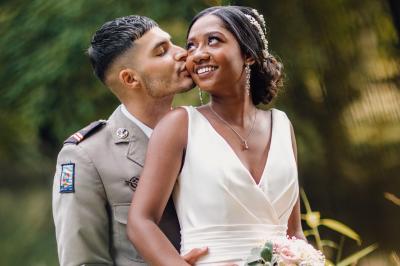 Un couple en tenue de mariage pose dans une forêt verdoyante, éclairée par une lumière douce.