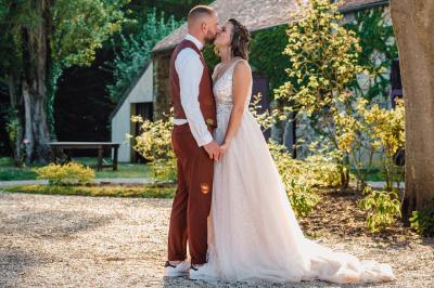 Un couple en tenue de mariage pose dans une forêt verdoyante, éclairée par une lumière douce.