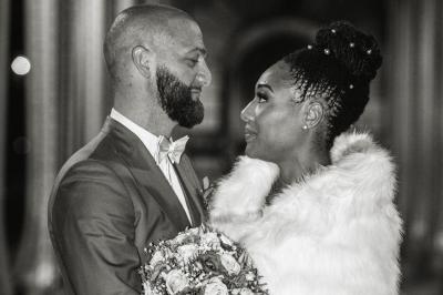 Un couple en tenue de mariage pose dans une forêt verdoyante, éclairée par une lumière douce.