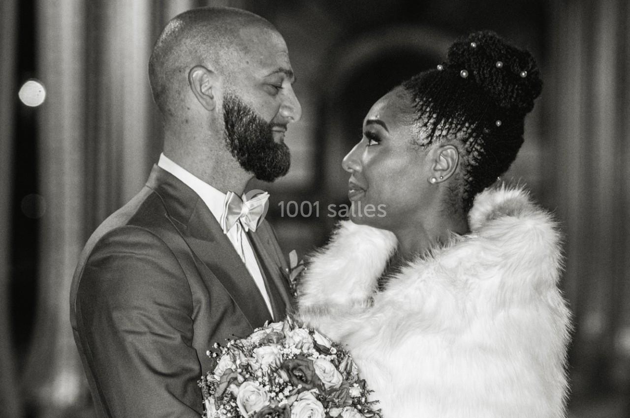Un couple habillé élégamment se regarde avec tendresse, tenant un bouquet de fleurs, dans une ambiance nocturne.
