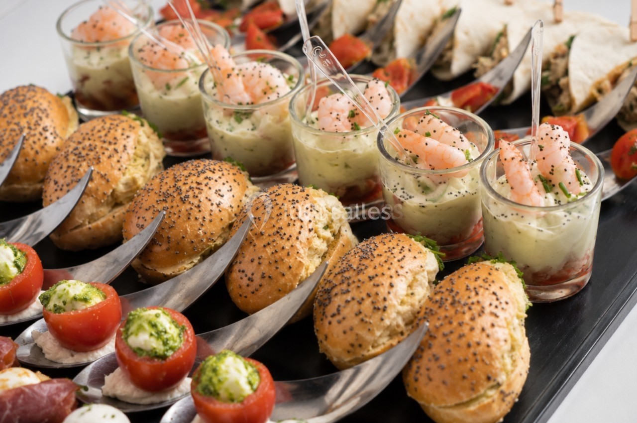 Plateau de bouchées apéritives variées comprenant mini-burgers, verrines de crevettes et tomates garnies.