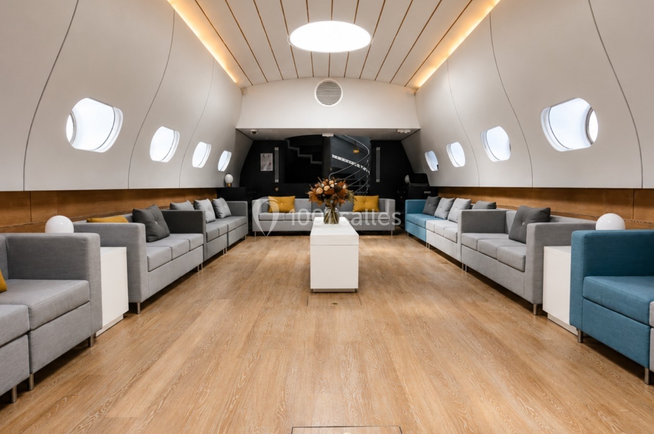 Intérieur spacieux et lumineux d'un avion aménagé avec des canapés modernes, des tables basses et un éclairage doux.