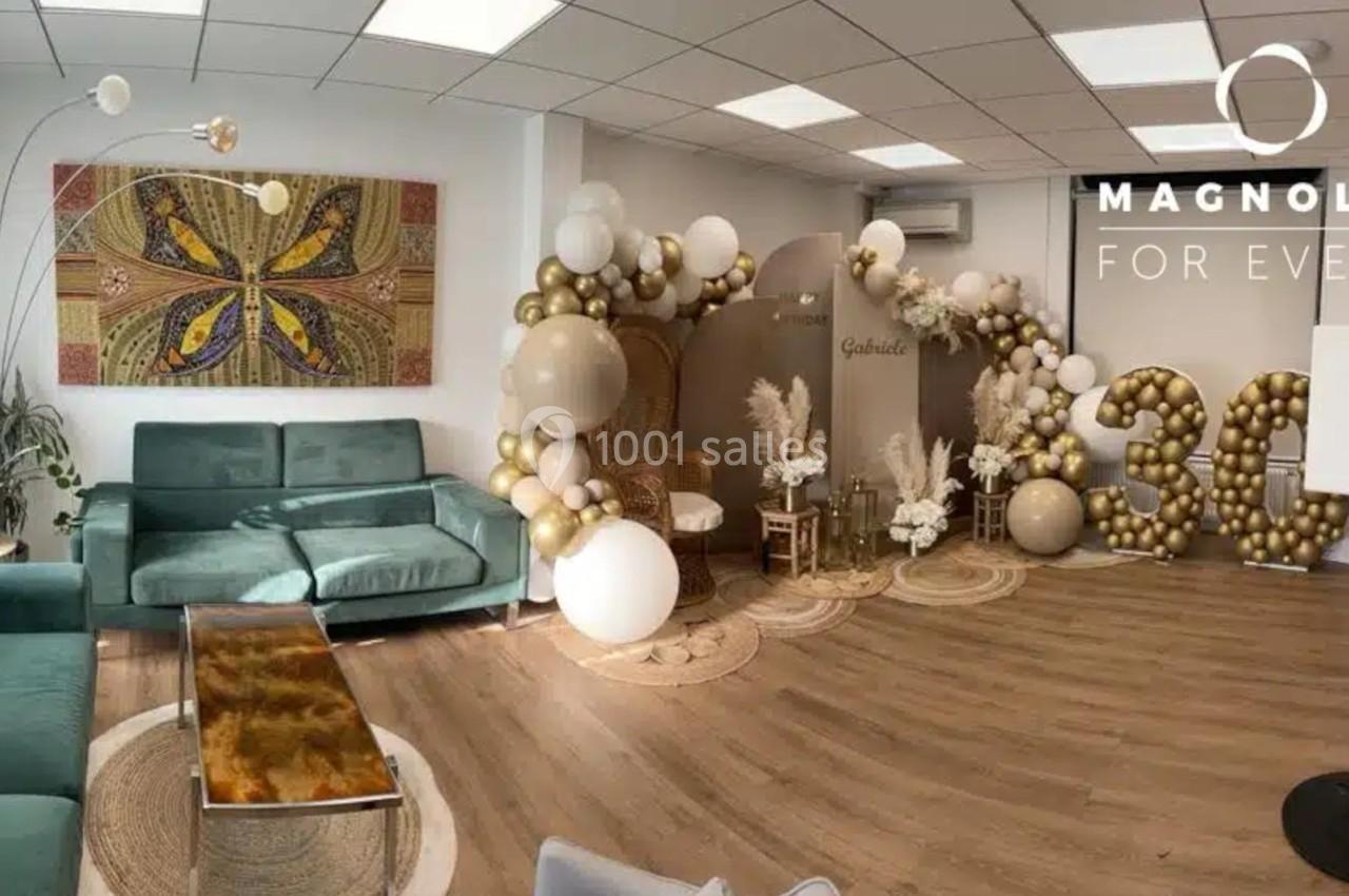 Décoration d'intérieur avec ballons dorés et blancs formant le chiffre 30, canapés verts et tableau mural coloré.